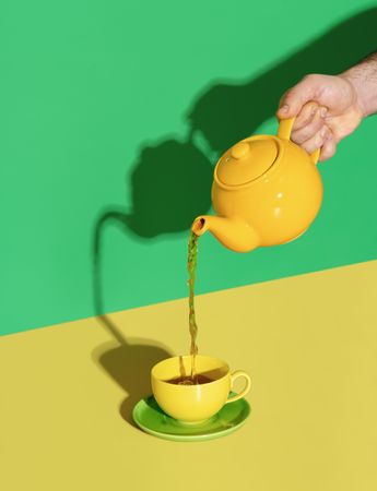 Pouring mint tea from a teapot in a cup, minimalist on a vibrant background