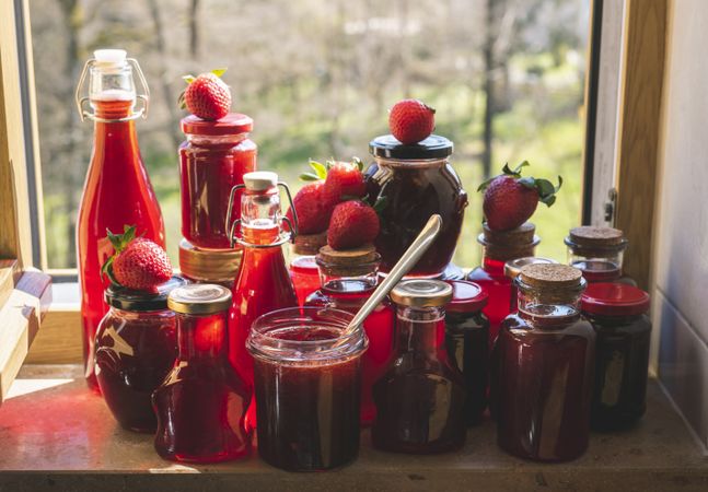 Strawberry syrup and jam jars on the window sill