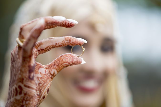 Woman's hands with henna tattoo on them holding ring