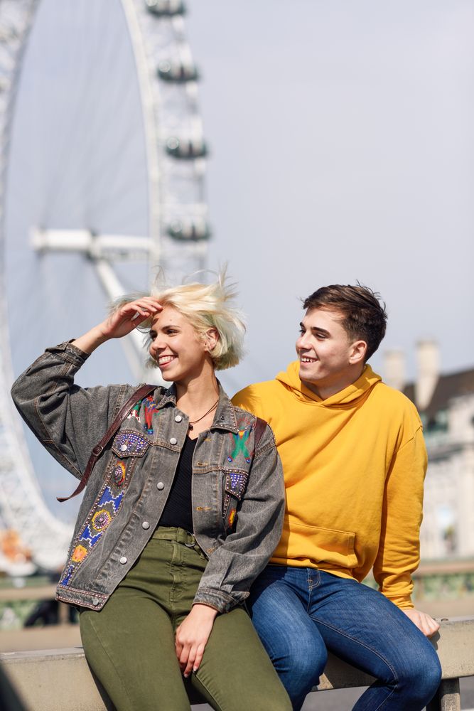 Man and woman friend sitting in front of London Eye