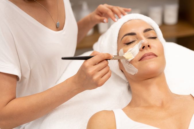 Female with towel on head having a relaxing face mask applied