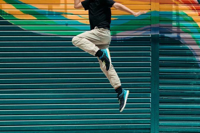 Person jumping against a brightly painted wall