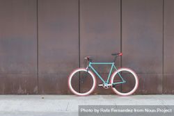 Red and green bicycle parked against a brown wall 5aRV84
