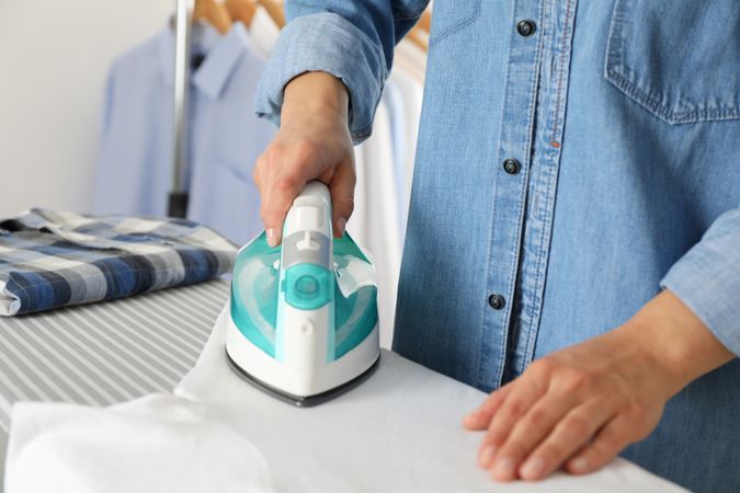 Young woman ironing shirt on ironing board, space for text