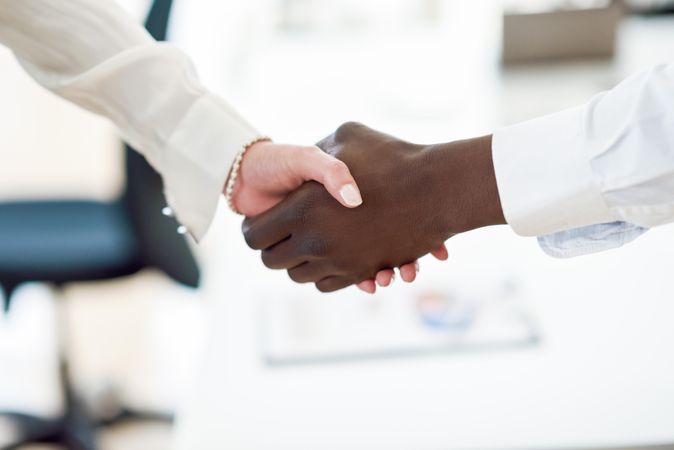 Close up of Black male and white female shaking hands in professional setting