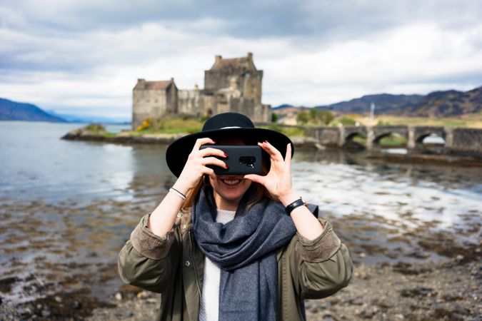 Smiling traveling woman photographing with phone