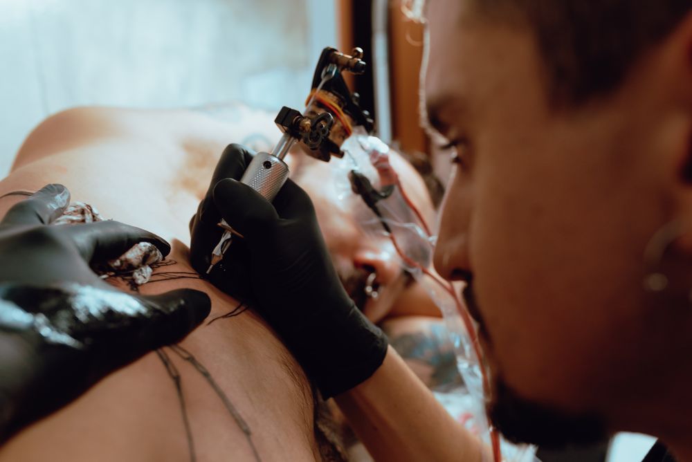 Man receiving tattoo on upper body