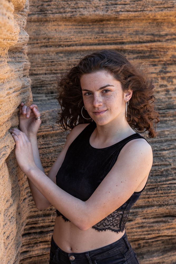 Young female leaning on sandstone rock