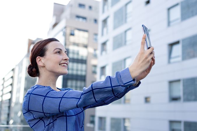 Smiling businesswoman taking selfie on street