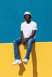 Happy Black man sitting on colorful wall