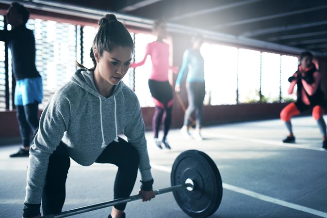 Woman reaching down to do deadlifts with bar bell