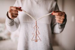 Woman holding up a Christmas tree ornament with ribbon