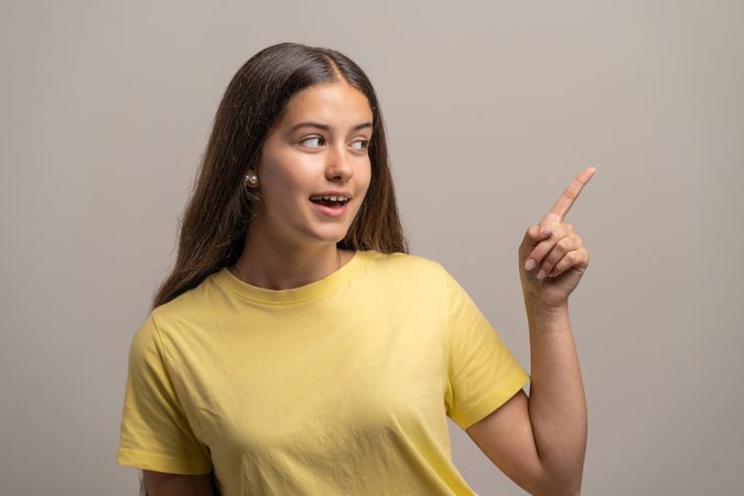 Surprised young woman pointing and looking at something with an amazed expression.