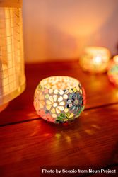 Lit candles in floral ornament on wooden table 5XAvv4