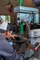 Male mechanic using drilling machine in workshop
