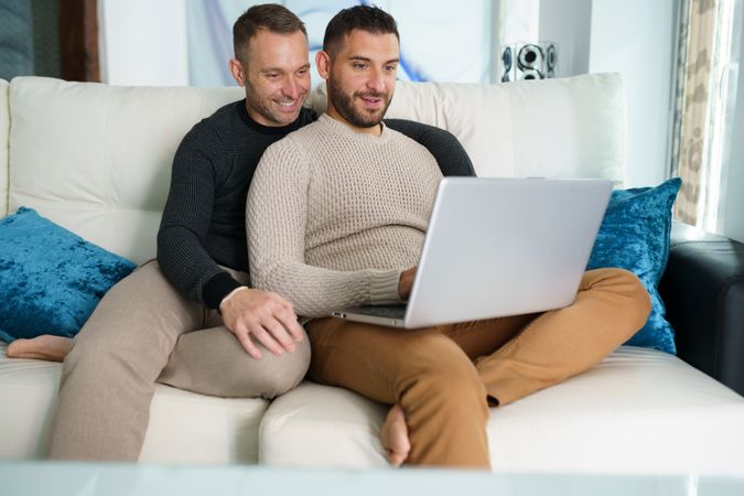 Two men cosy on couch with laptop