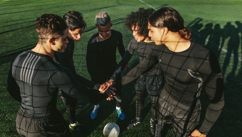 Soccer team putting their hands in a stack as they prepare to play game