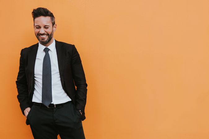 Adult stylish man in costume near orange wall
