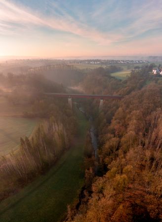 Railway bridge crossing river in winter nature, drone shot at sunrise