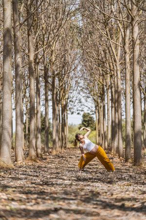 Adult expectant mother practicing yoga in park during sunny day