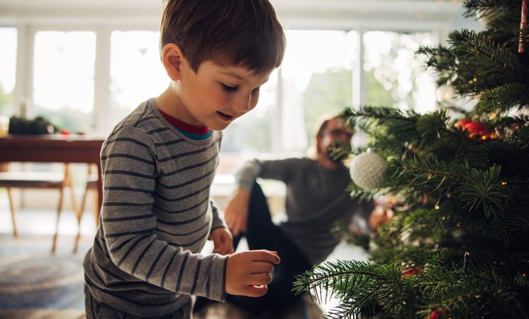 Boy playing by christmas tree