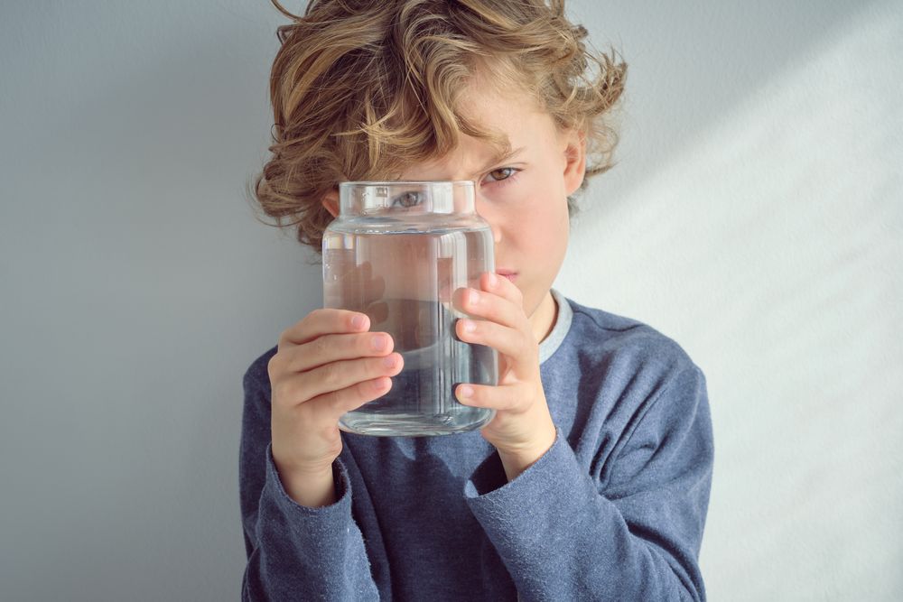 Blond haired boy with jar of water