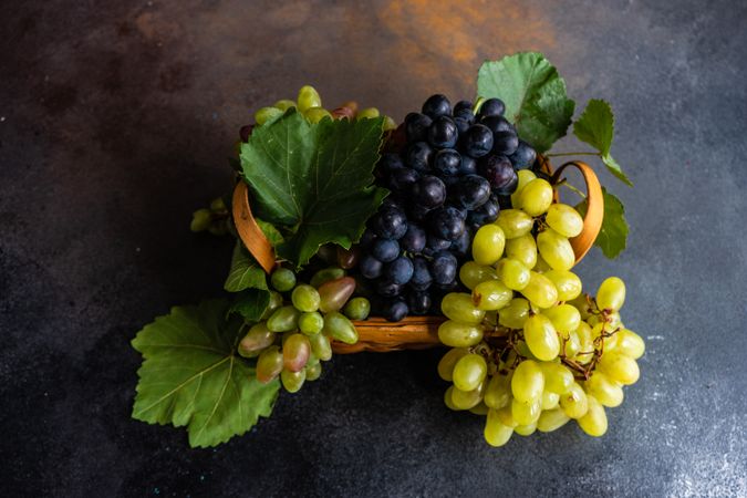 Box of fresh green & red grapes on grey kitchen counter