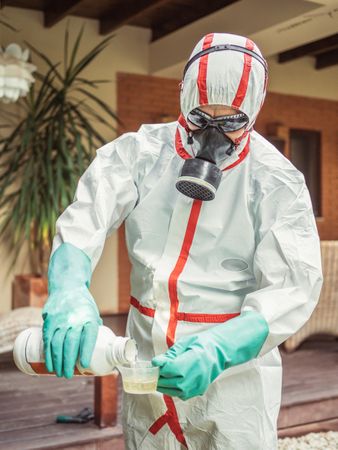 Man in suit for fumigation pouring chemical into tank
