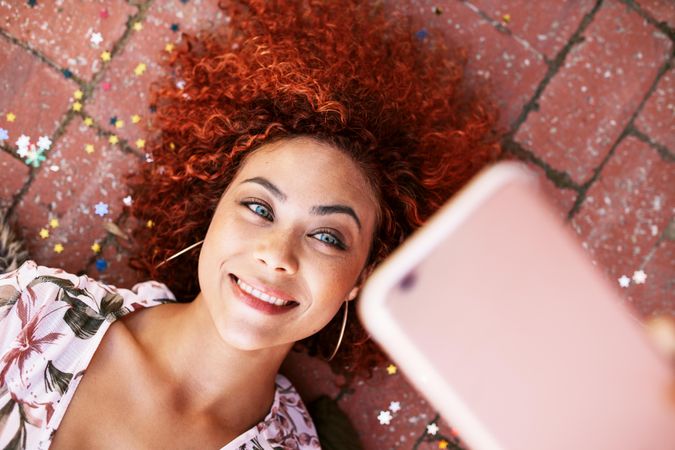 Woman posing for a selfie lying on the ground