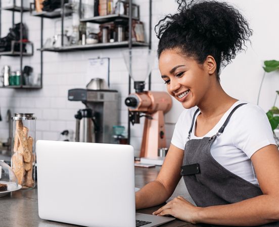 Small business owner working on laptop in her cafe 