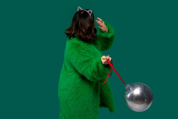 Woman holds large silver Christmas ornament.