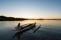 Woman in boat admiring lake at sunset