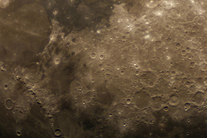 Magnified view of the moon’s cratered surface in golden light