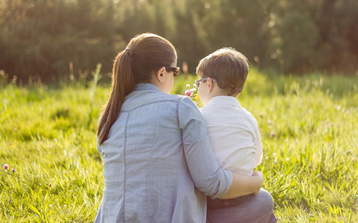 Son giving bouquet of flowers to mother in field