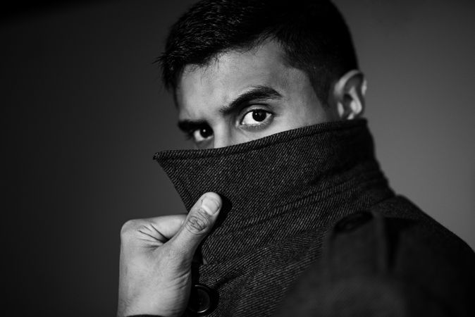 Grayscale photo of man hiding his mouth behind jacket