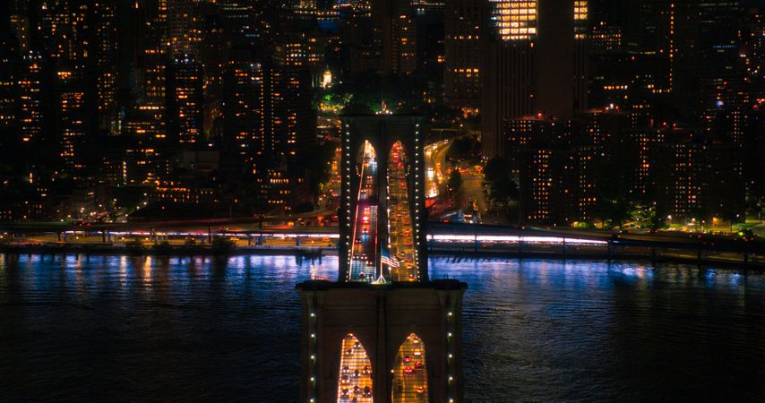 Aerial Top Down Night Scenery with Brooklyn Bridge with Car Traffic Moving in Both Directions on the Road. Helicopter Bird's-Eye View of a Popular American Travel and Business Destination