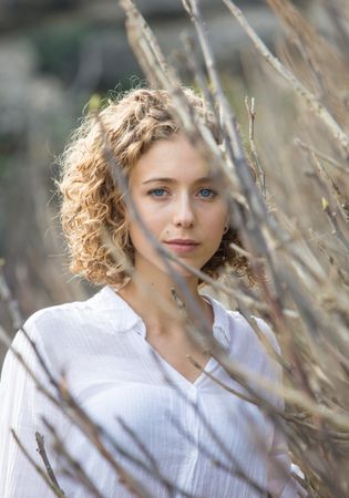 Young woman near dry twigs of bushes