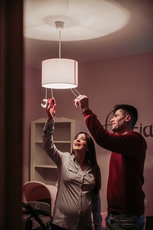 Expecting couple lighting chandelier in baby room