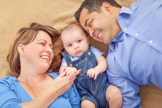Young Couple Laying With Their Infant On A Blanket