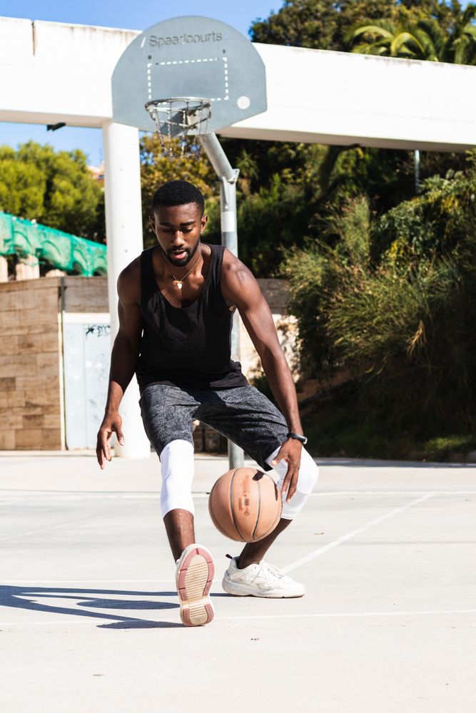 Black man playing basketball on sports ground