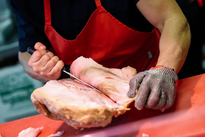Close up of butcher cutting ham on cutting board