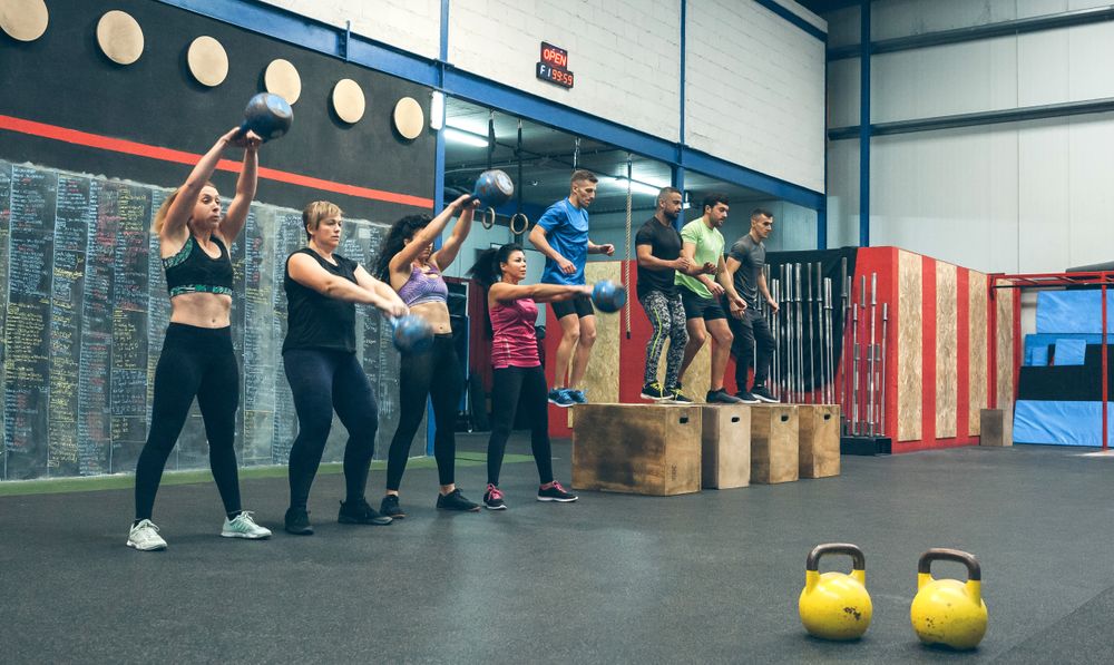 Sportswomen with kettlebells and sportsmen in background