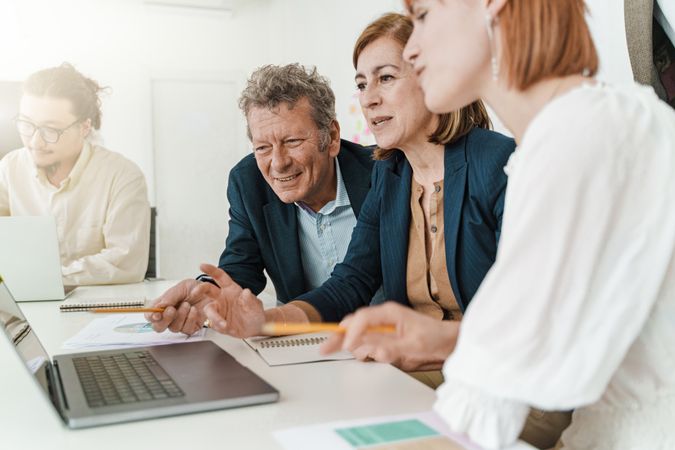Three colleagues engage in a collaborative discussion, observing the screen of a laptop
