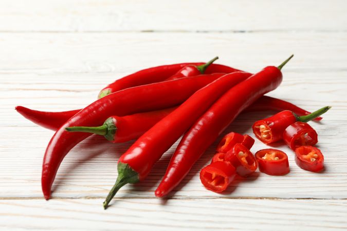 Bunch of chilli peppers on plain wooden background, close up