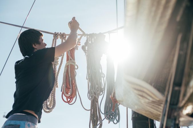 Man tying ropes on yacht