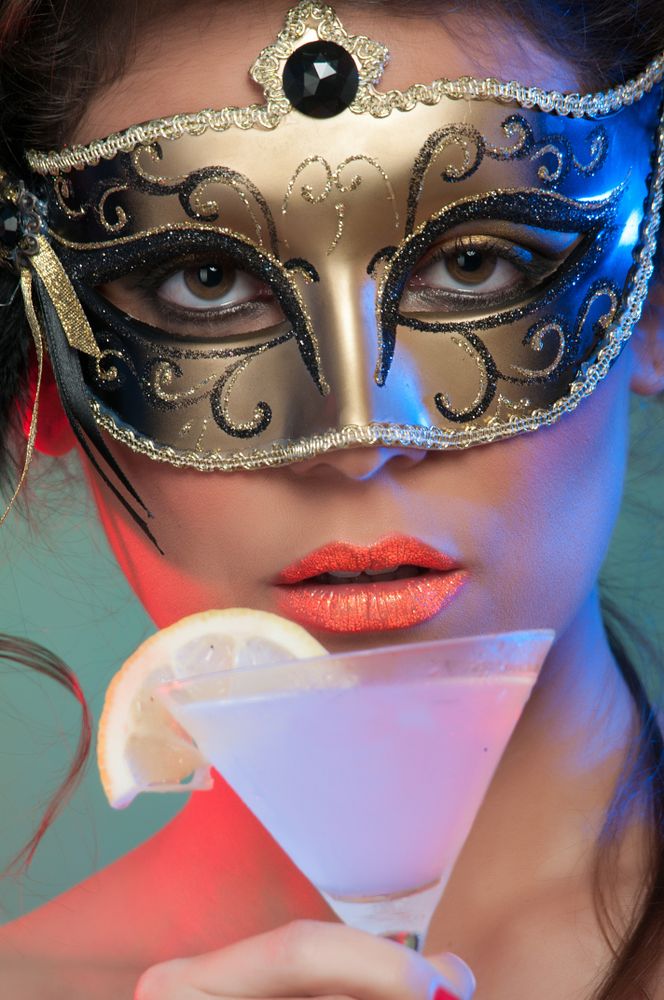 Woman in mask holding glass of drink