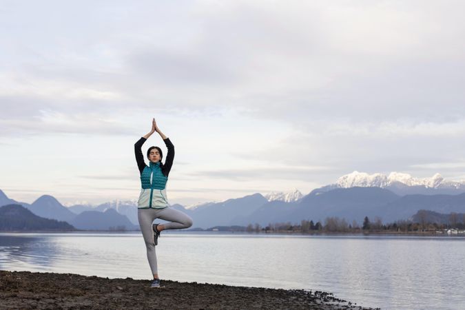 Young woman practicing yoga near the lake edge