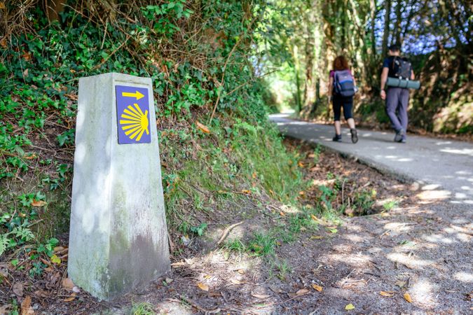 Milestone of Saint James way with pilgrims walking