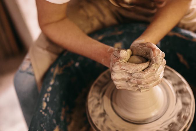 Potter moulding clay on pottery wheel in artist's studio