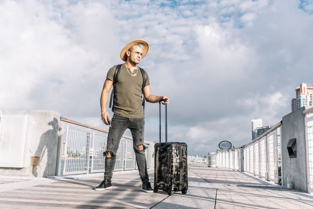 Traveler man with a hat walking with suitcase in the street